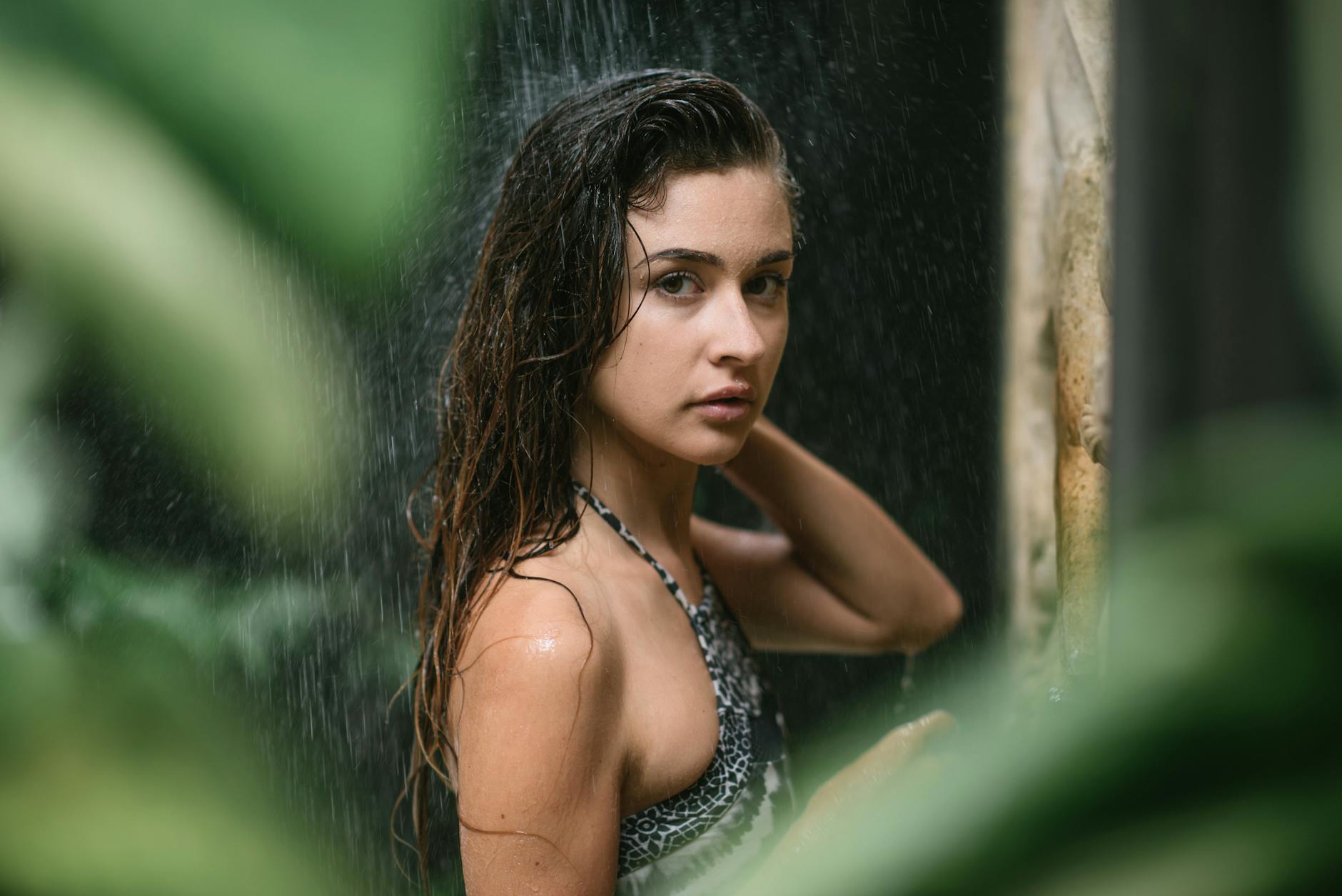 young lady in swimsuit standing among tropical plants